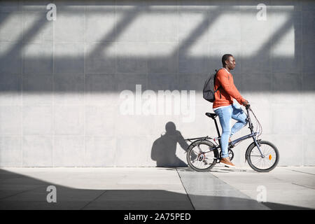 African Man Riding Folding Bike For Urban Commuting Stock Photo