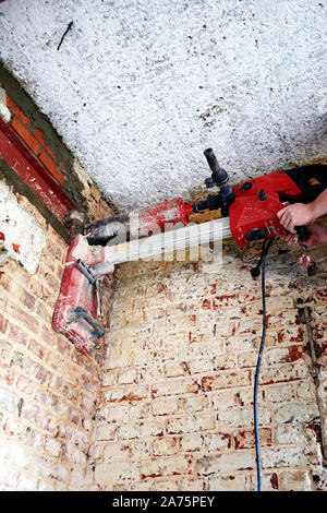 Professional laborer pierce a big round hole in a brick wall Stock Photo