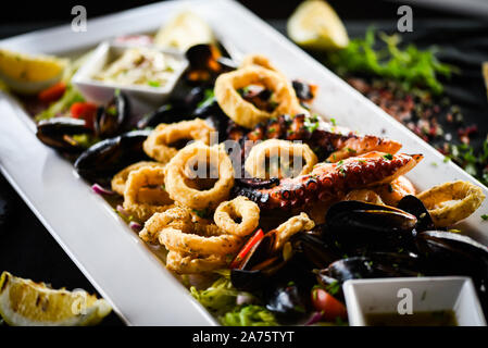 delicious mix fried seafood dish with octopus, shrimps, prawns, shells, squids & fresh fish - with lemon & herbs dressing Stock Photo