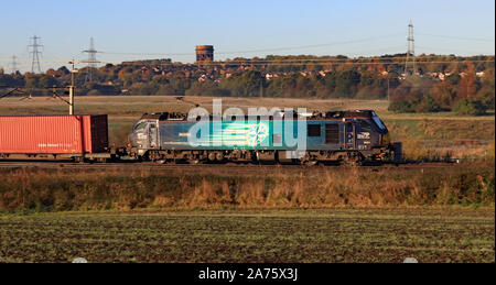 A DRS locomotive passes Daresbury near Runcorn on a bright autumn morning.  The train is carrying intermodal containers from Daventry to Glasgow Stock Photo