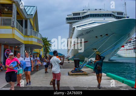 Nassau, Bahama - September 21,2019: A young woman poses in front of a cruise ship as other tourtist walk by at prince George Warf on New Providence Is Stock Photo