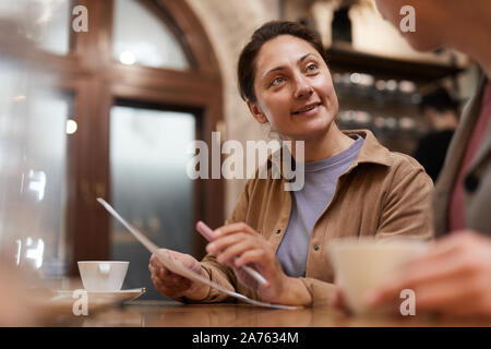 Mature businesswoman holding business contract and discussing it with her colleague at the table Stock Photo