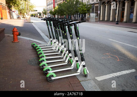 row of lime-s electric scooters neatly stacked in a row kerbside early morning downtown louisville kentucky USA Stock Photo