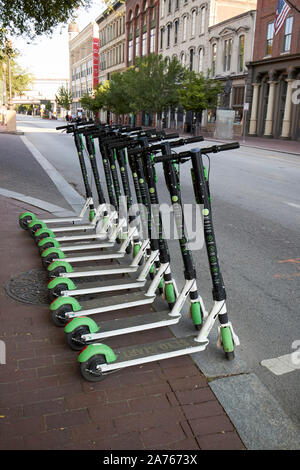 row of lime-s electric scooters neatly stacked in a row kerbside early morning downtown louisville kentucky USA Stock Photo