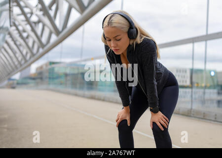 Tired Woman Resting With Hands On Knees After Running Workout Stock Photo