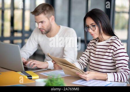 Wife in glasses looking at post mail while sitting near husband Stock Photo