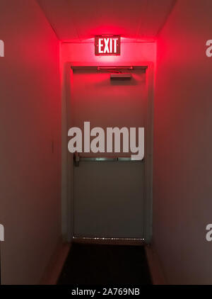 Emergency exit door at the end of the hall with the exit light on. Stock Photo