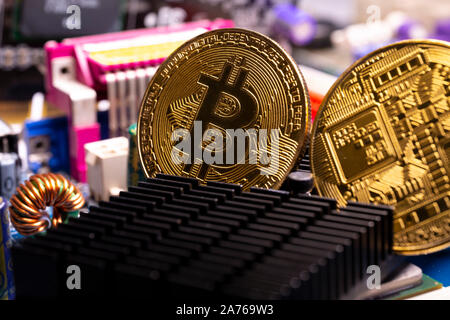 Virtual cryptocurrency money Bitcoin golden coins on a computer printed circuit board PCB. The future of money. Computational equipment. Stock Photo
