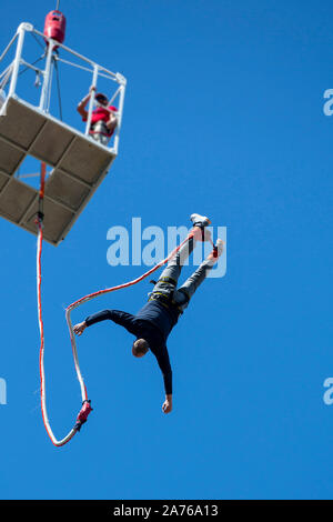 A man jumps with a bungee from a crane top against the blue sky. Unrecognizable person. Stock Photo