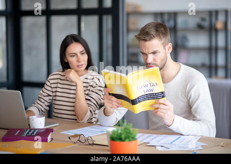 Blue-eyed husband feeling involved in studying new tax law Stock Photo