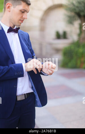 Happy groom waiting for bridea and looking at watch. Stock Photo