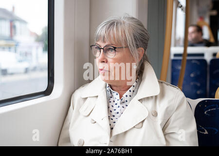 Senior woman sitting on train looking out window Stock Photo
