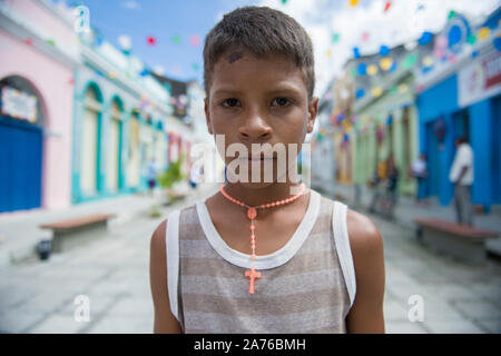 Marechal Deodoro, Alagoas, Brazil - June 21, 2016: Religious little boy among the colorful decoration of pennants during June Parties (Festa Junina) Stock Photo
