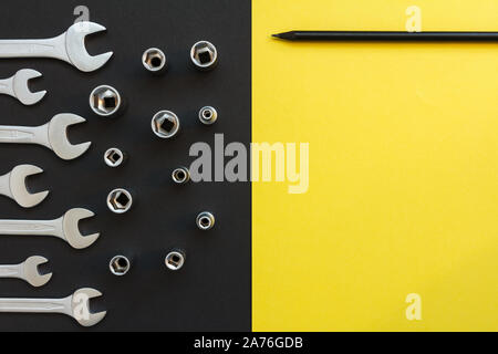 Flat Lay Composition With Different Construction Tools on Black and Yellow Background. Top View of Checklist and Working Tools, Wrench, Screwdriver Stock Photo
