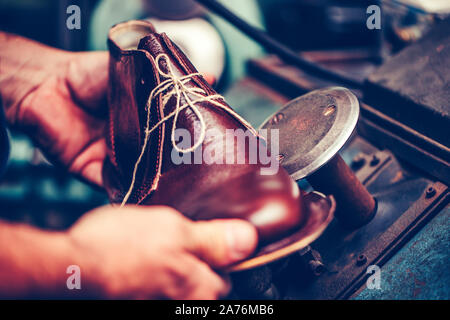 Experienced shoemaker using special machine tool for making a shoes The process of making shoes. Stock Photo