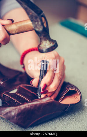 Close up of a female shoemaker working with leather using crafting tools Stock Photo
