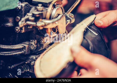 Hands of an experienced shoemaker stitching a part of the shoe at a workshop Stock Photo