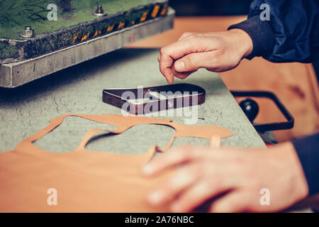 Close up of a shoemaker and cutting leather in the handmade footwear industry Stock Photo