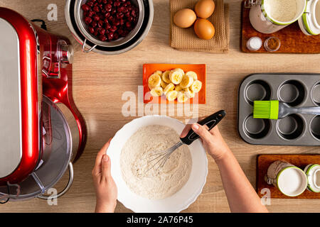 Hand whisked flour, banana slices, cherries and other ingredients for muffin making Stock Photo
