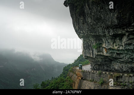 Small bus taking dangerous sharp turn on the winding road of 99 turns to the top of the Tianmen Mountain, Zhangjiajie Stock Photo