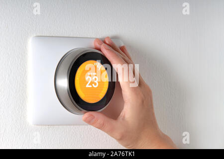 Smart Thermostat with a hand setting up the temperature Stock Photo