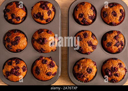 Top view of two trays banana-cherry muffins with its light brown background Stock Photo