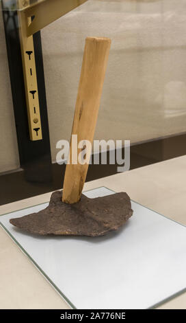 Montilla, Spain - March 2nd, 2019: Roman hoe. Agricultural iron tool with replica wooden handle and original wide head. Montilla Local History Museum, Stock Photo