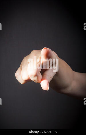 Female finger pointing at you closeup on black background Stock Photo