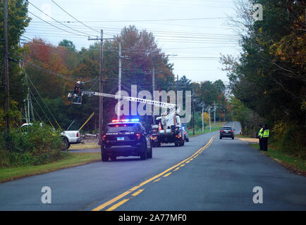 Berlin, CT USA. Oct 3 2019. Police vehicle accompanying telecommunications personnel in hydraulic man lift installing new cable lines. Stock Photo