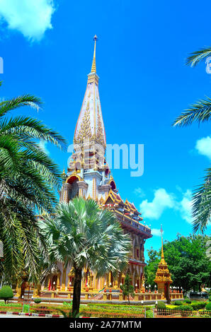 The main chedi taken from a distance with palm trees to the front at Chalong Temple Phuket Thailand