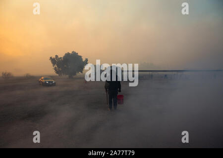 Simi Valley, California, USA. 30th Oct, 2019. A resident tries to remove hidden fire near houses in Simi Valley, the United States, Oct. 30, 2019. An aggressive wildfire erupted Wednesday morning on the hillsides above Simi Valley, triggering a new round of evacuation in Southern California. The blaze, dubbed Easy Fire, was first reported around 6:15 a.m. local time, then spread to about 972 acres as of 9 a.m., Ventura County fire Capt. Brian McGrath told local KTLA news channel. Credit: Xinhua/Alamy Live News Stock Photo