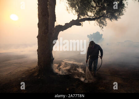 Simi Valley, California, USA. 30th Oct, 2019. A resident tries to remove hidden fire near houses in Simi Valley, the United States, Oct. 30, 2019. An aggressive wildfire erupted Wednesday morning on the hillsides above Simi Valley, triggering a new round of evacuation in Southern California. The blaze, dubbed Easy Fire, was first reported around 6:15 a.m. local time, then spread to about 972 acres as of 9 a.m., Ventura County fire Capt. Brian McGrath told local KTLA news channel. Credit: Xinhua/Alamy Live News Stock Photo