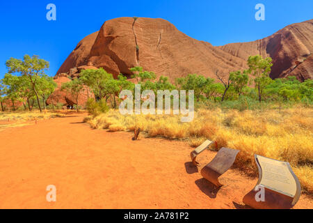 Uluru, Northern Territory, Australia - Aug 24, 2019: Kuniya and Liru Site which tells Uluru's creation stories along Uluru Base Walk in sand path of Stock Photo