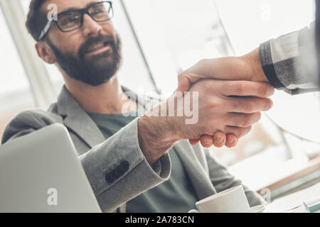 Male startupers working together at office sitting handshake close-up guy smiling cheerful Stock Photo
