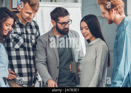 Startupers working together at office standing discussing project joyful Stock Photo