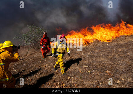 Simi Valley, United States. 30th Oct, 2019. A photographer takes pictures of firefighters during the Easy Fire near the Ronald Reagan Presidential Library in Simi Valley, California. The fire spread quickly due to strong Santa Ana winds with wind gusts reaching up to 70 mph in some areas. The National Weather Service issued a rare extreme red flag warning to the greater Los Angeles area. The fire prompted mandatory evacuations. Credit: SOPA Images Limited/Alamy Live News Stock Photo