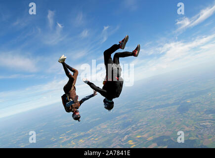 This skydiving freefly team is training the head down position together. Each team member has fun and is smiling in his upside down facing position. Stock Photo