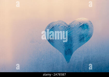 The heart icon on foggy window. Abstract blue background. Pattern of wet glass, cool texture in rainy day. Symbol of love. Romantic concept. Stock Photo