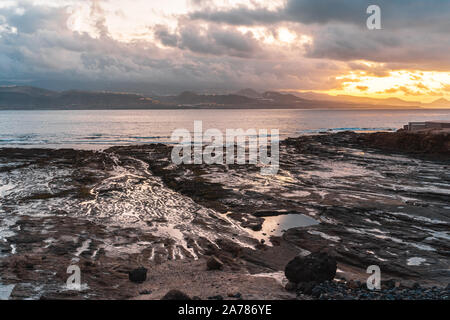 Sunset with some clouds on a rocky coast in Gran Canaria Stock Photo