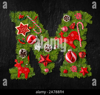 Letter M made of Christmas tree ornaments on a black slate background Stock Photo