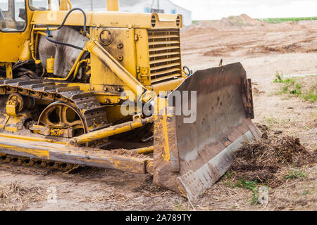 Close-up of crawler bulldozer truck. Earthmoving heavy machinery. Yellow crawler machinery. Yellow Tractor on caterpillar tracks, tractor tracks Stock Photo