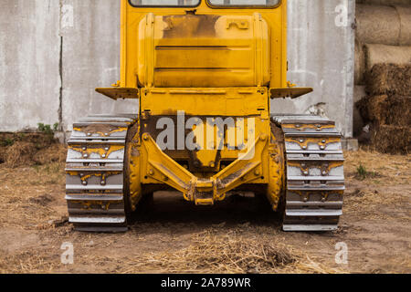 Close-up of crawler bulldozer truck. Earthmoving heavy machinery. Yellow crawler machinery. Yellow Tractor on caterpillar tracks, tractor tracks Stock Photo