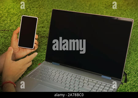 Man holds the smartphone with black screen lying on the carpet near the black-screened laptop. Digital devices for domestic internet access. Usage of Stock Photo