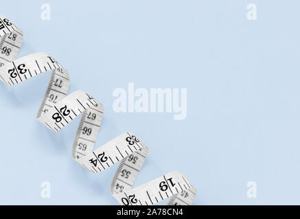 White measuring tape isolated on a blue background, with copy space Stock Photo