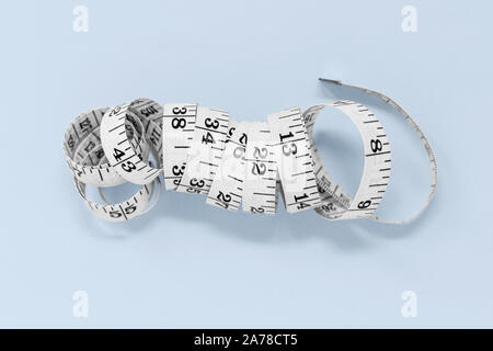 Coil of measuring tape isolated on a blue background, with copy space Stock Photo