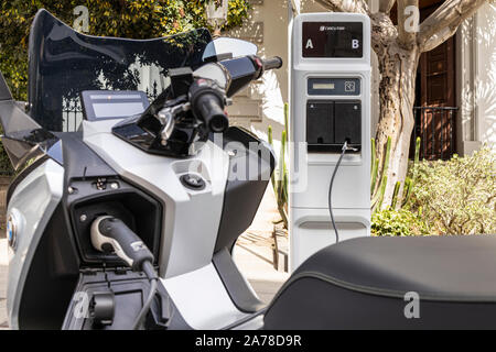 BMW C Evolution electric scooter, motorcycle, plugged in to a Circutor charging point on a street in Santa Cruz de Tenerife, Canary Islands, Spain Stock Photo