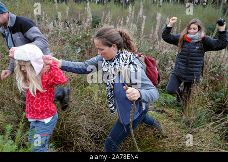 Family parents child holding hands walking through marshland in countryside in autumn in Carmarthenshire Wales UK  KATHY DEWITT Stock Photo