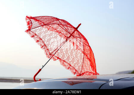 Red sunny lace umbrella reflected on the roof of the car. Israel Stock Photo