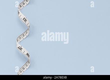 White measuring tape isolated on a blue background, with copy space Stock Photo