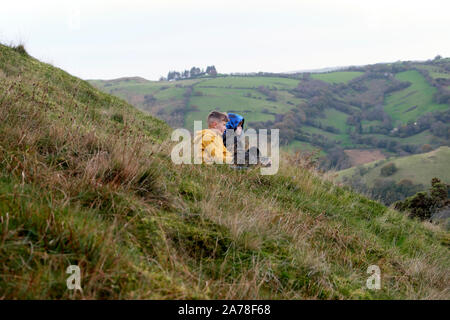 Two boys walking in the countryside have a rest and talk on a hillside and look at the landscape in autumn in Carmarthenshire Wales UK  KATHY DEWITT Stock Photo